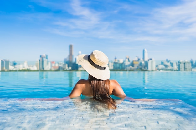 Free photo portrait beautiful young asian woman relaxing around outdoor swimming pool with city view