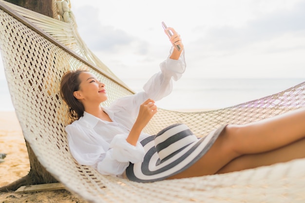 Free photo portrait of beautiful young asian woman relaxing on hammock around beach in vacation