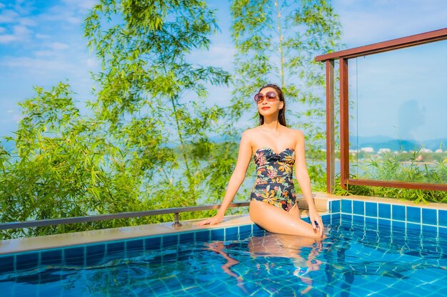 Portrait of beautiful young asian woman relaxing in outdoor swimming pool with sea ocean view