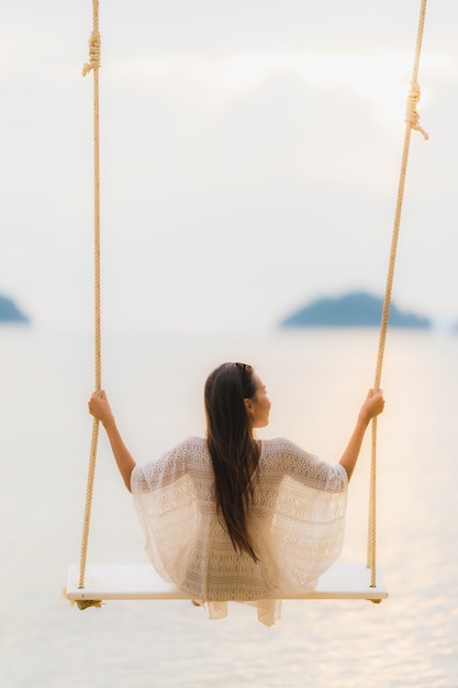 Free photo portrait beautiful young asian woman sitting on the swing around beach sea ocean for relax