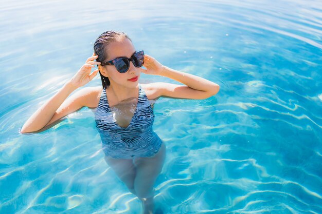 Portrait beautiful young asian woman smile happy relax around swimming pool in hotel resort for leisure