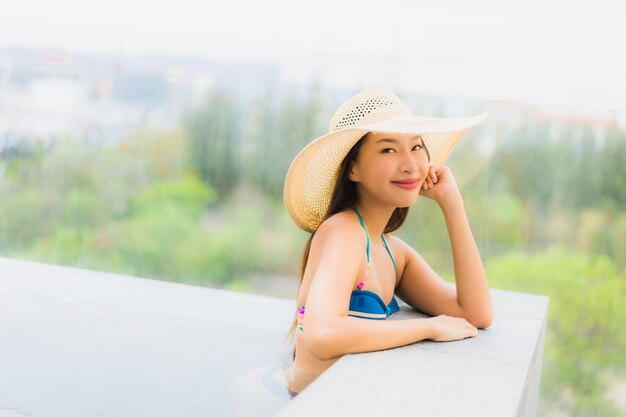 Portrait beautiful young asian woman smile happy relax around swimming pool in hotel resort for leisure