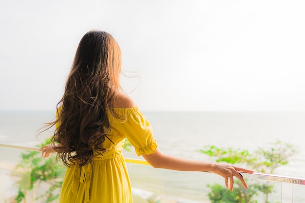 Portrait beautiful young asian woman smile happy and relax at outdoor balcony with sea beach and oce