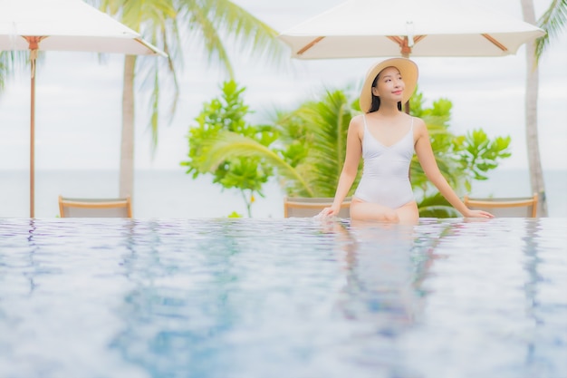 Free photo portrait beautiful young asian woman smile relax around outdoor swimming pool in resort hotel on holiday vacation travel trip