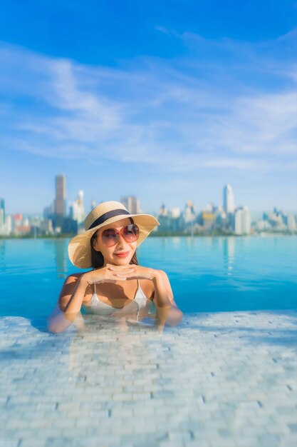 Portrait beautiful young asian woman smile relax leisure around outdoor swimming pool with city view