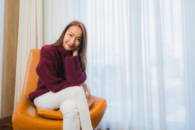 Portrait beautiful young asian woman smile relax on sofa in living room interior