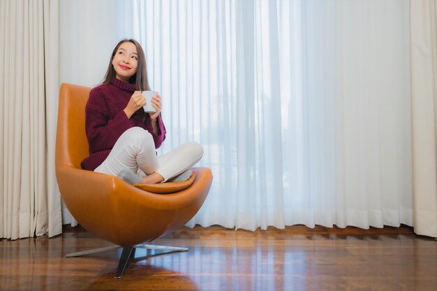 Portrait beautiful young asian woman smile relax on sofa in living room interior