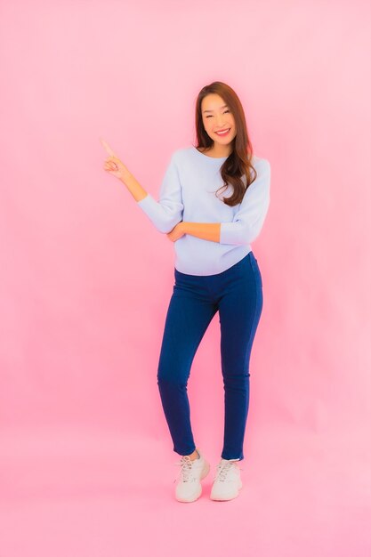 Portrait beautiful young asian woman smile with action on pink isolated wall