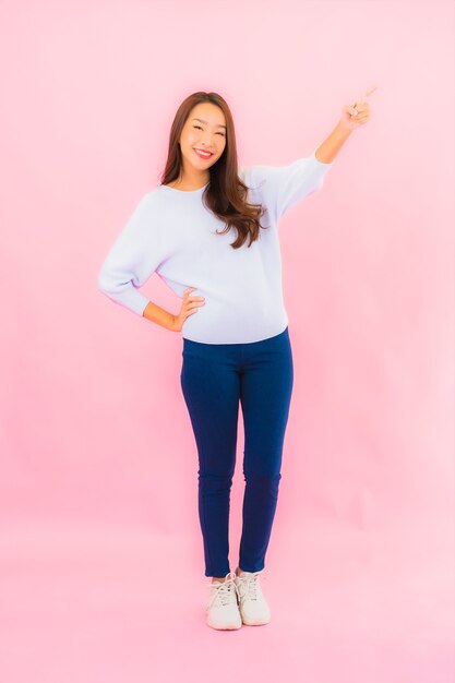 Portrait beautiful young asian woman smile with action on pink isolated wall