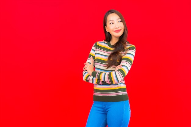 Portrait beautiful young asian woman smile with action on red isolated wall