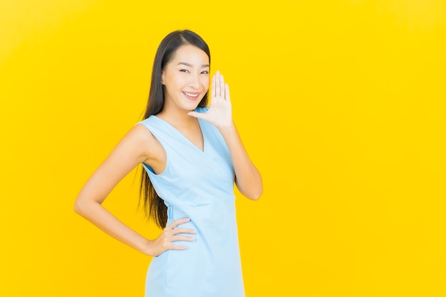 Portrait beautiful young asian woman smile with action on yellow color wall