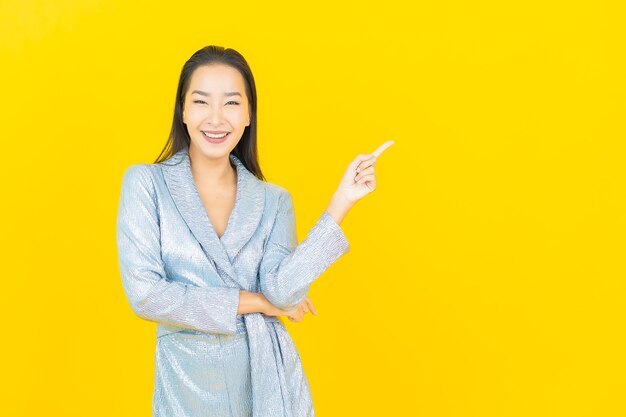 Portrait beautiful young asian woman smile with action on yellow wall