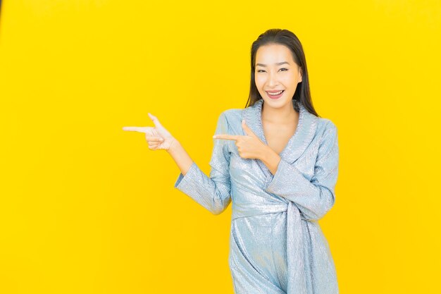 Portrait beautiful young asian woman smile with action on yellow wall