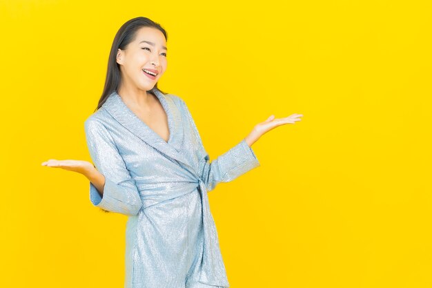 Portrait beautiful young asian woman smile with action on yellow wall