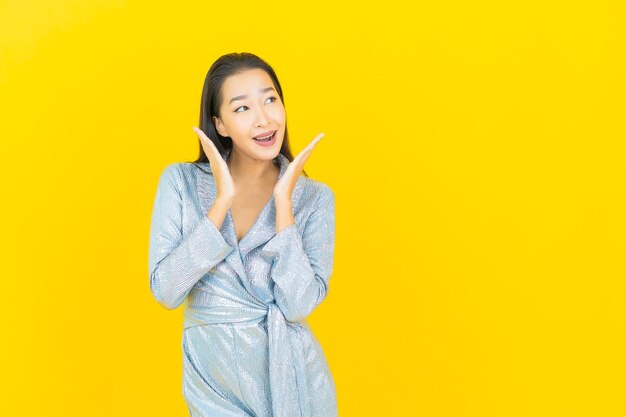 Portrait beautiful young asian woman smile with action on yellow wall