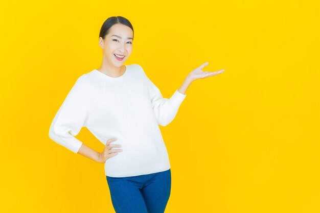 Portrait beautiful young asian woman smile with action on yellow