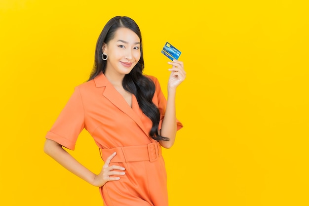 Portrait beautiful young asian woman smile with credit card on yellow