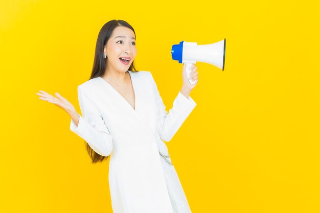 Portrait beautiful young asian woman smile with megaphone on yellow color background