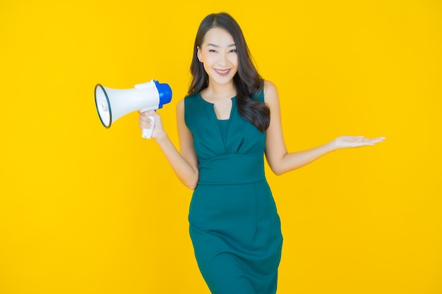 Portrait beautiful young asian woman smile with megaphone on yellow