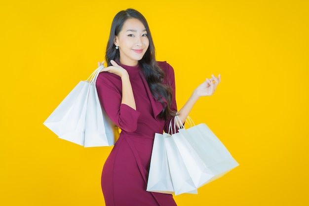 Portrait beautiful young asian woman smile with shopping bag on yellow