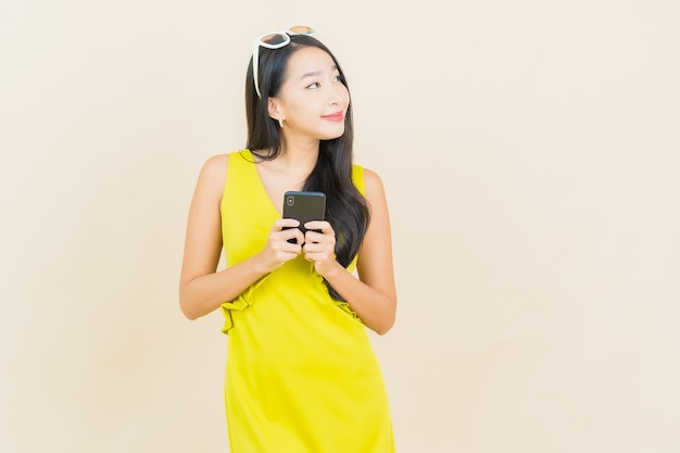 Portrait beautiful young asian woman smile with smart mobile phone on color wall