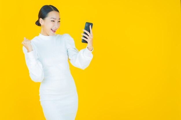 Portrait beautiful young asian woman smile with smart mobile phone on yellow