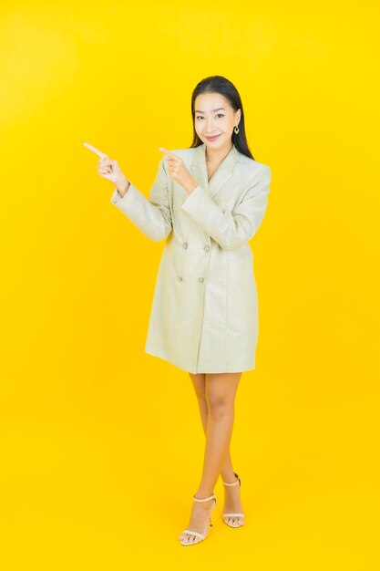 Portrait beautiful young asian woman smiles and points to the left on color wall