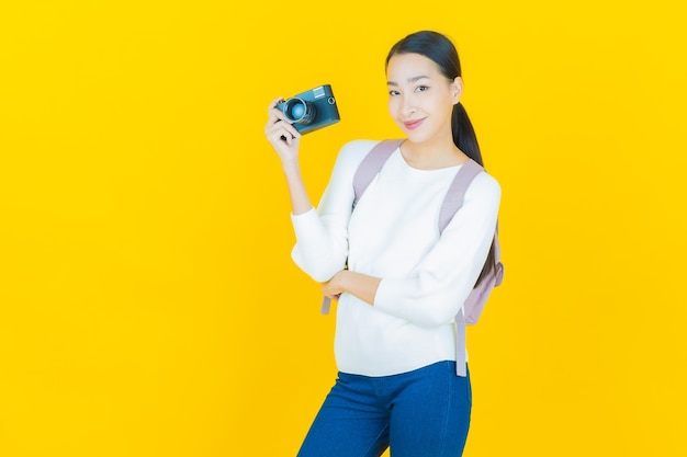 Portrait beautiful young asian woman use camera on yellow