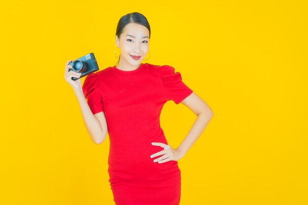 Portrait beautiful young asian woman use camera on yellow