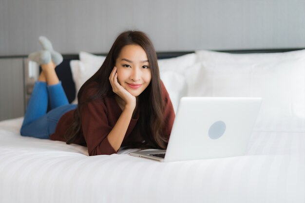 Portrait beautiful young asian woman use computer laptop on bed in bedroom interior