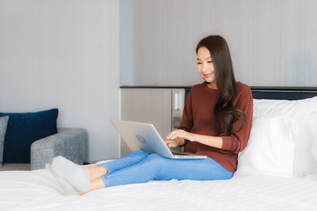 Portrait beautiful young asian woman use computer laptop on bed in bedroom interior