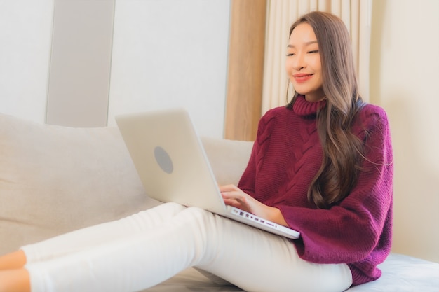 Portrait beautiful young asian woman use computer laptop on sofa in living room interior