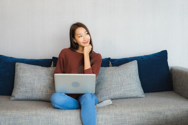 Portrait beautiful young asian woman use computer laptop on sofa in living room interior