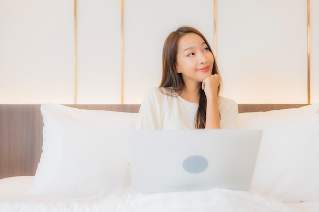 Portrait beautiful young asian woman use laptop on bed in bedroom interior