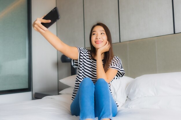 Portrait beautiful young asian woman use smart mobile phone in bedroom