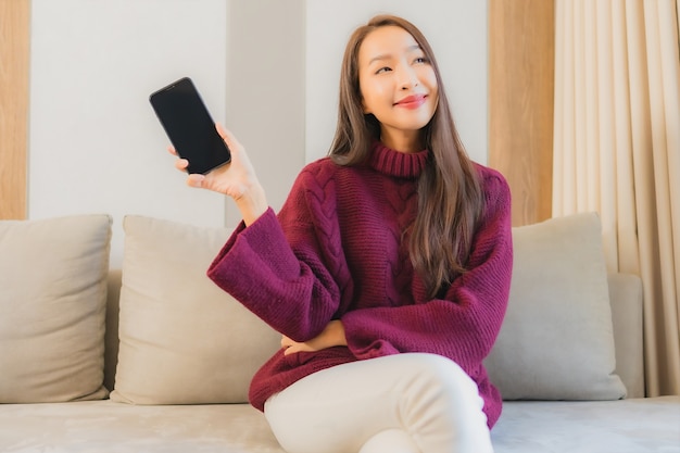 Portrait beautiful young asian woman use smart mobile phone on sofa in living room interior