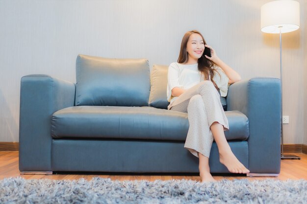 Portrait beautiful young asian woman use smart mobile phone on sofa in living room interior