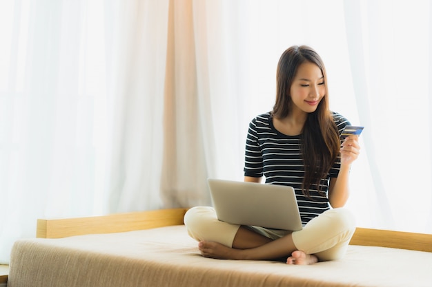 Portrait beautiful young asian woman using computer notebook or laptop with credit card for shopping