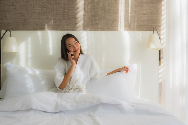 Portrait beautiful young asian woman using smart mobile phone on bed in bedroom