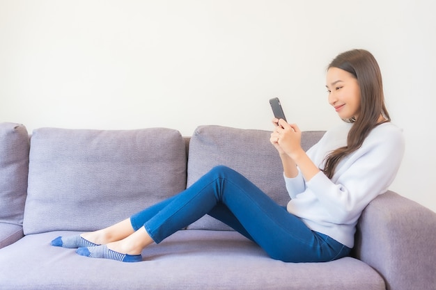 Portrait beautiful young asian woman using smart mobile phone on sofa in living room interior