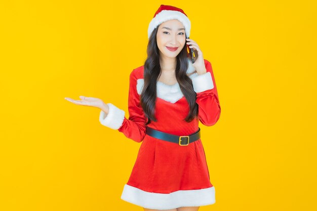 Portrait beautiful young asian woman wear christmas costume with mobile phone on yellow