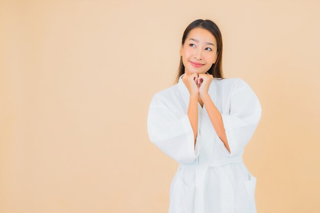 Free photo portrait beautiful young asian woman wearing bathrobe with smile on beige