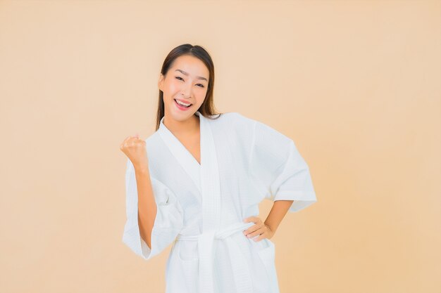 Portrait beautiful young asian woman wearing bathrobe with smile on beige