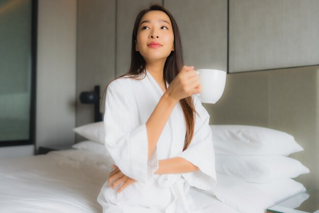 Portrait beautiful young asian woman with coffee cup in bedroom