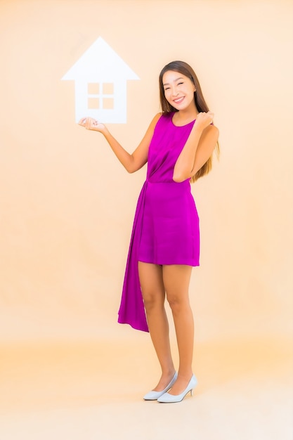 Portrait beautiful young asian woman with home sign board on color isolated background