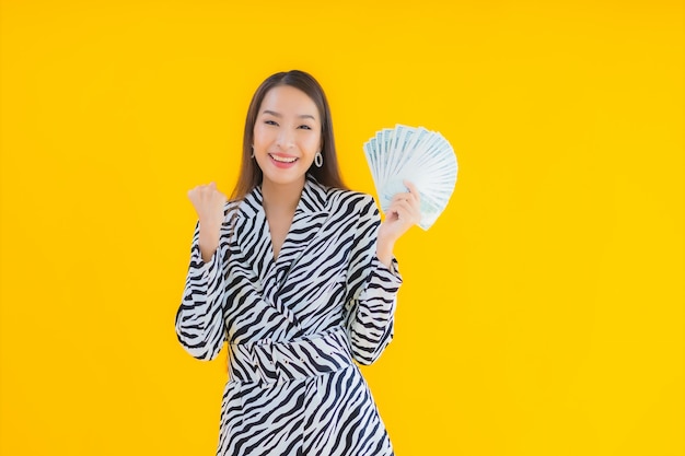 Portrait beautiful young asian woman with a lot of cash and money on yellow