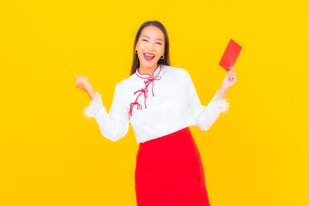 Portrait beautiful young asian woman with red envelopes letter in chinese new year on yellow