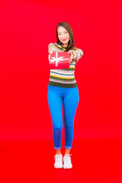 Portrait beautiful young asian woman with red gift box on red wall