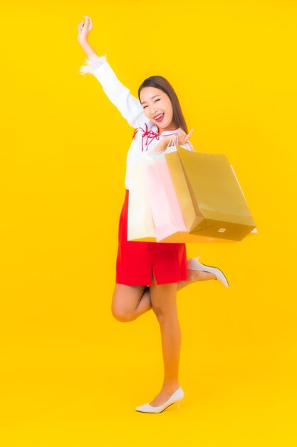 Portrait beautiful young asian woman with shopping bag and credit card on yellow