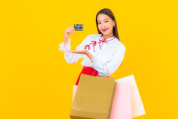 Portrait beautiful young asian woman with shopping bag and credit card on yellow